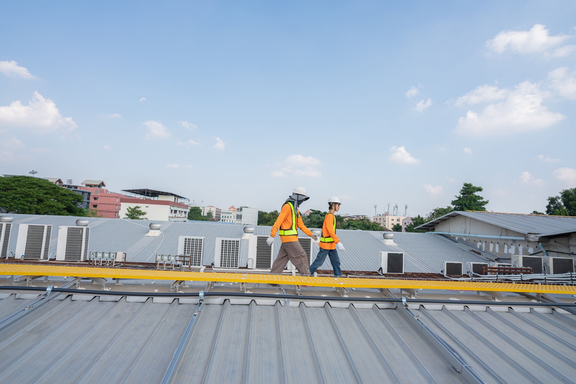 Men technicians carrying photovoltaic solar moduls on roof.