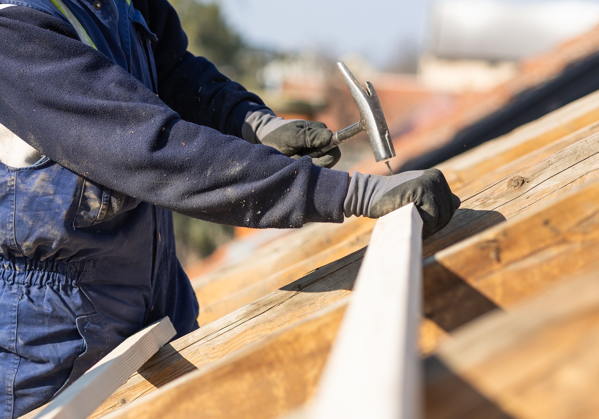 Roofer carpenter works on roof.